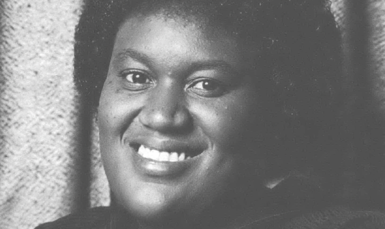 Black and white photo portrait of Black woman smiling at camera