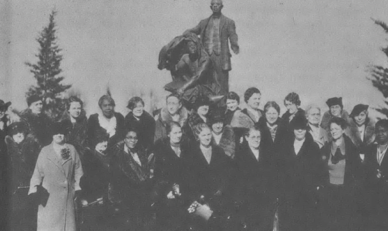 Black and white nineteenth century photo of group of white women standing in front of monument