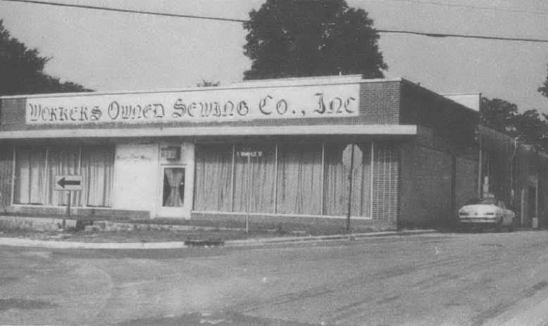 Black and white photo of Workers' Owned Sewing Co. one-story building and empty parking lot