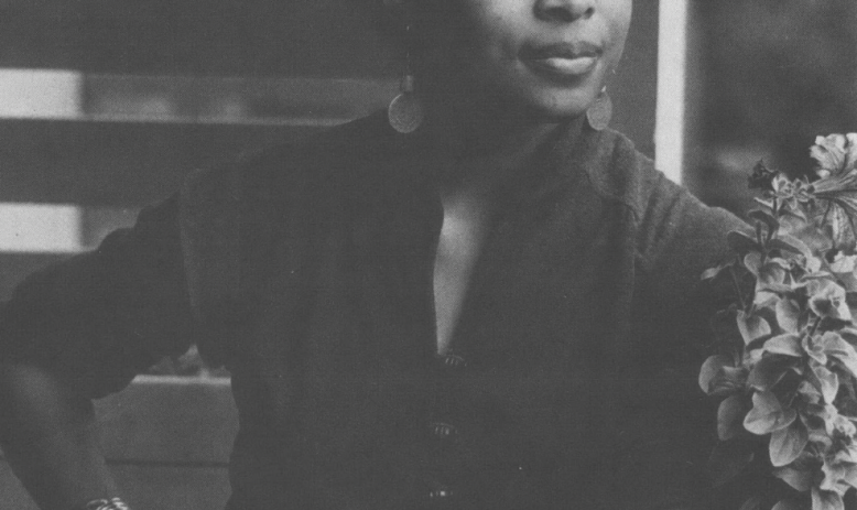 Black and white photo of Alice Walker leaning on porch railing looking into distance
