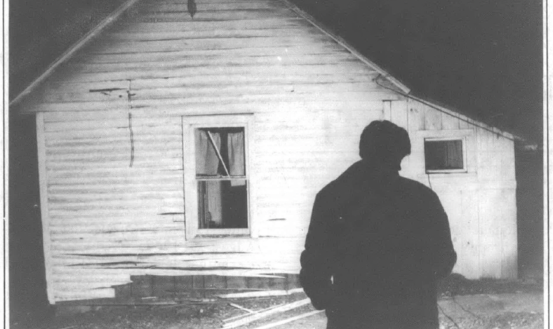 shadowed figure in front a bombed house