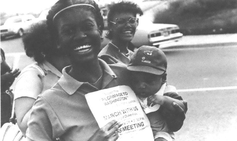 Woman holding baby and poster about the Carrollton-to-Washington March