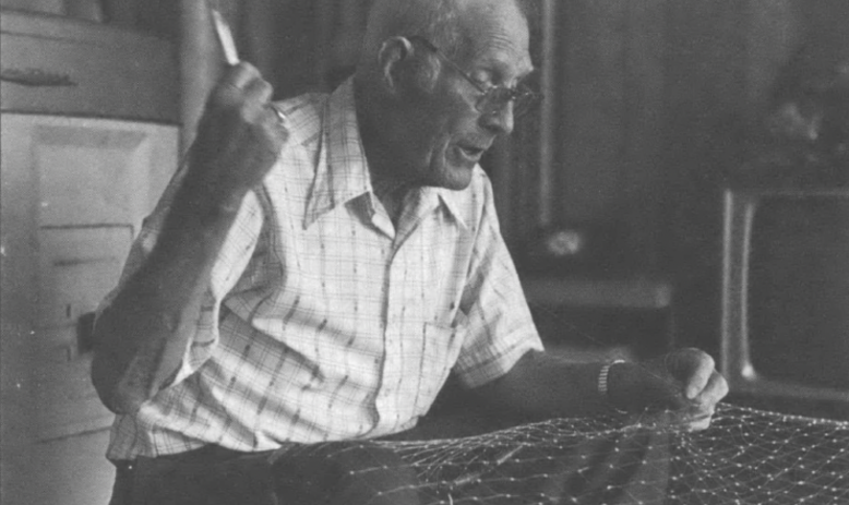 Earl Guthrie sewing a cast net in living room