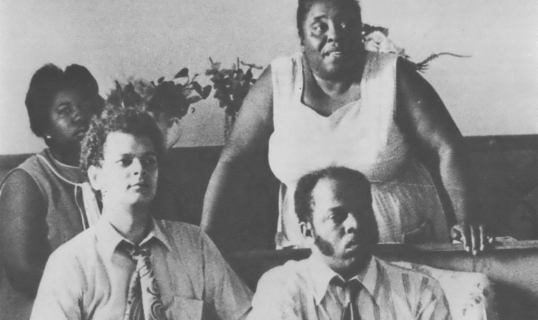 A black and white photo of Annie Divine, Fannie Lou Hamer, Julian Bond, and John Lewis seated at an event. 