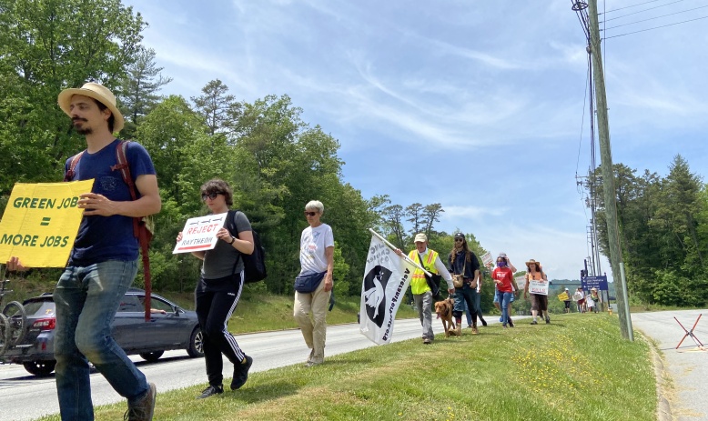 A line of marchers holding signs alongside a highway.