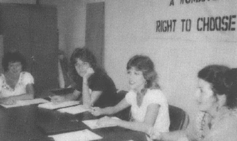 Women at a table with a "A Woman's Right to Choose" banner above them