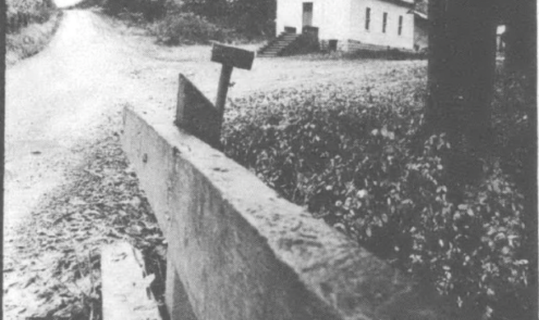 black-and-white photograph of a road with a church in the backgrounf