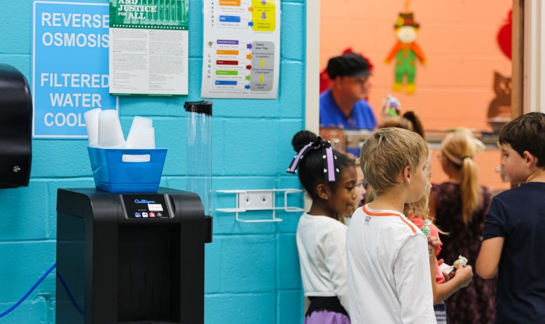 Children in school hallway standing near reverse osmosis water filtration drinking station