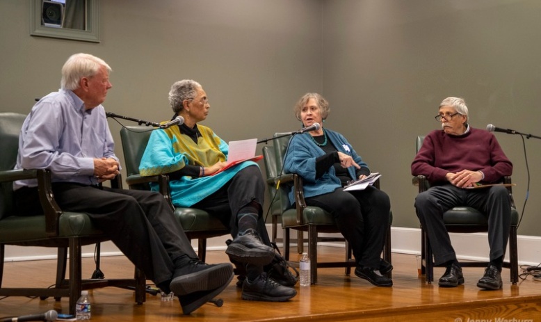 Four people sitting in chairs on a stage