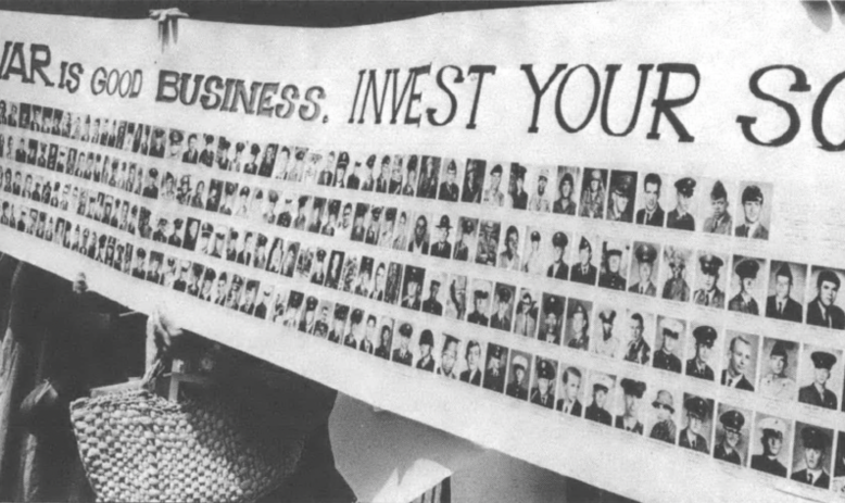 Banner reading "War is good business, invest your son" with multiple photos of enlisted men underneath