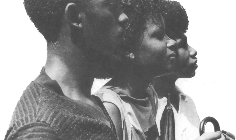 Black man and 2 Black women standing side by side looking right