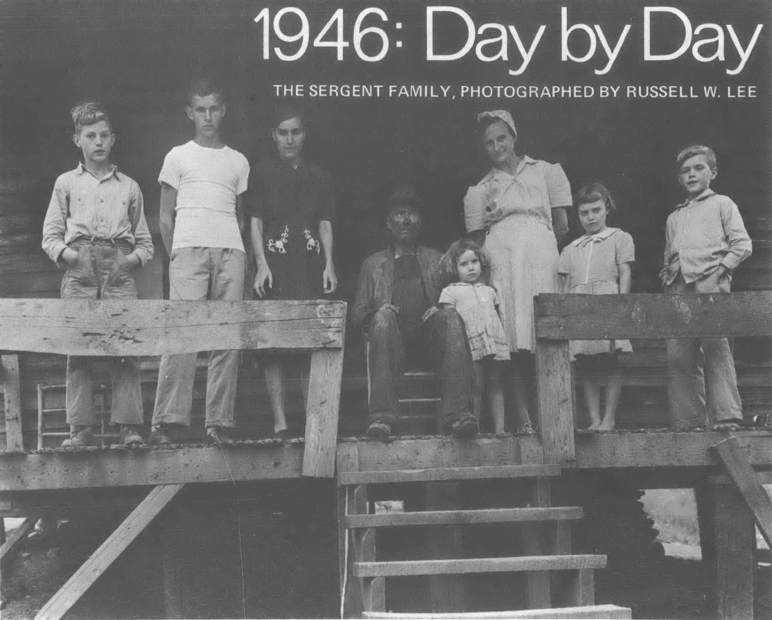 Black and white photo of white family, roughly 8 people, posed on wooden porch