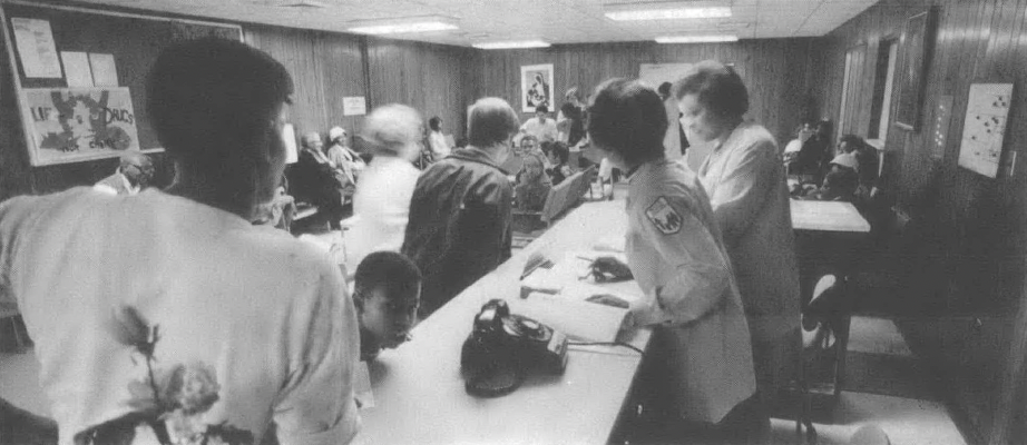 Black and white photo of people crowded around long tables