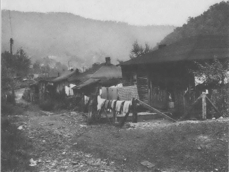 Black and white photo of clothes hanging on drying line outside house