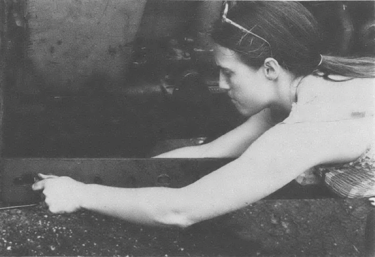 Black and white photo of woman stretched out and working on some kind of contraption