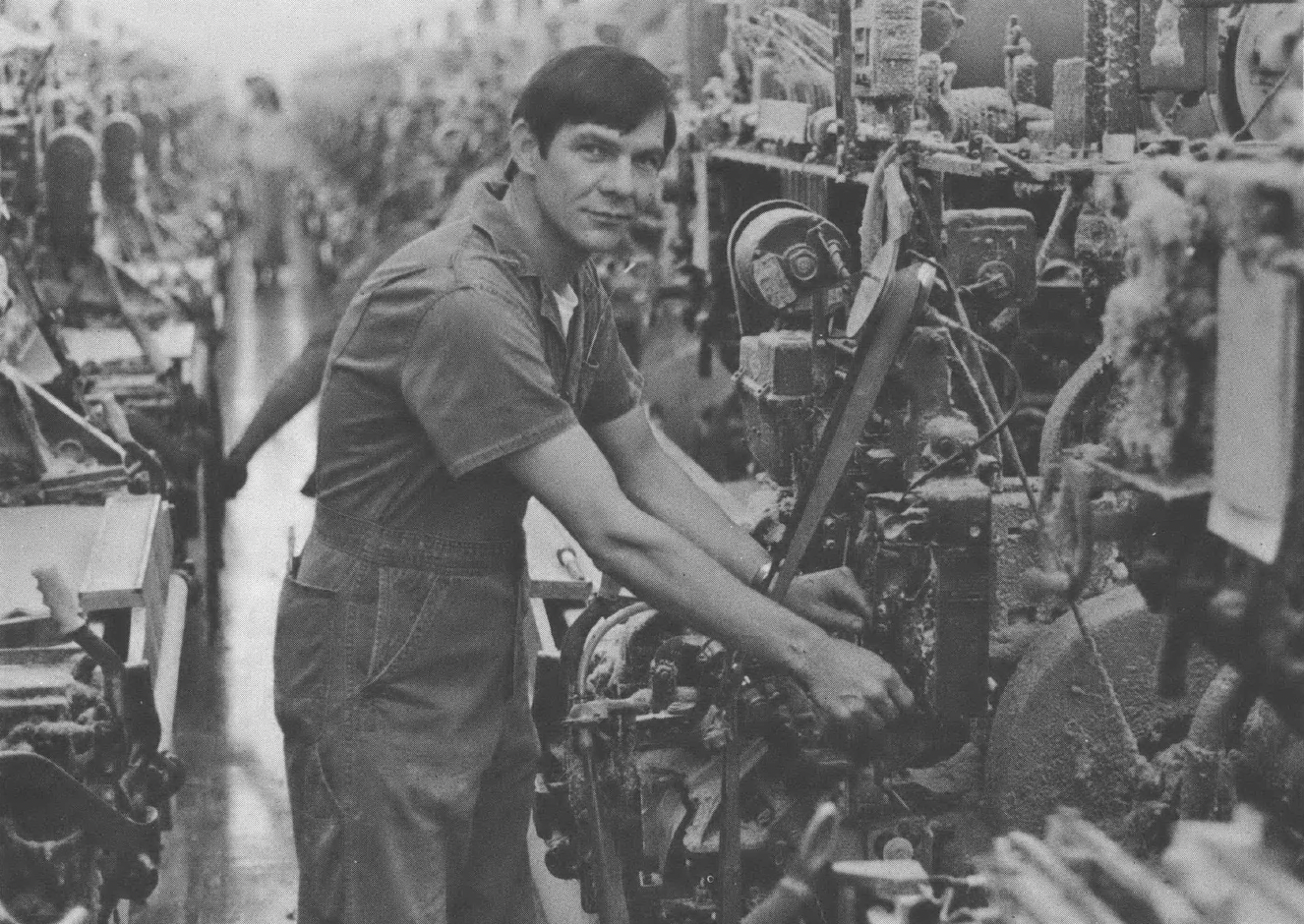 Black and white photo of man standing at machine