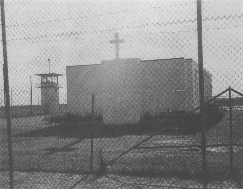A white church behind a prison fence, next to a guard tower