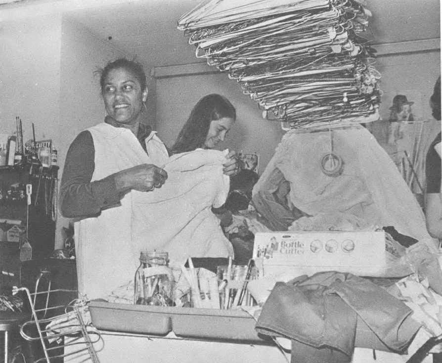 Black and white photo of women standing and working in an office