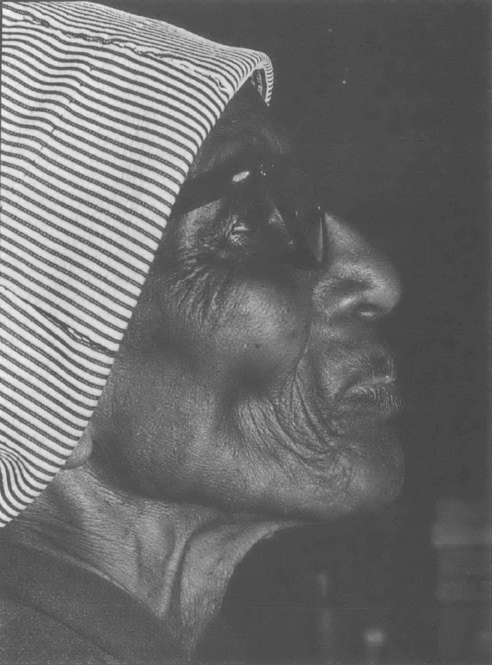 Black and white side profile photo of older Black woman wearing a hat and looking up