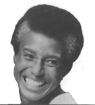 Black and white photo of Black woman with grey streaks in her hair smiling 