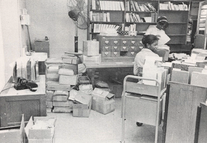 Black and white photo of two Black women in a file room