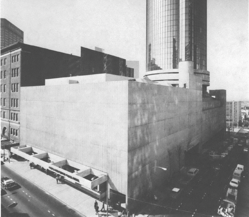 Black and white photo of building with glass-windowed tower that takes up entire city block