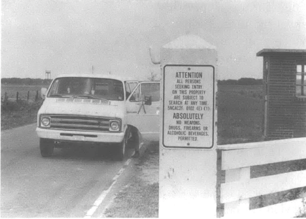 Black and white photo of white van pulling up to gate
