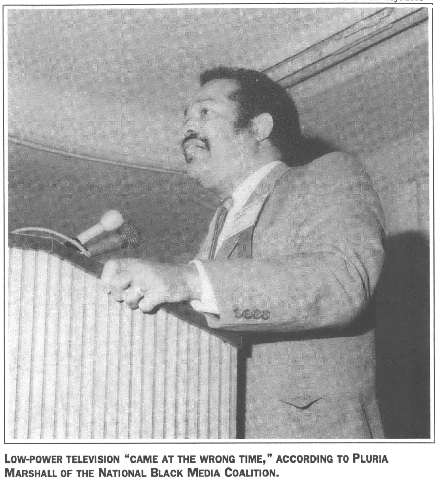 Man at a podium speaking in a suit 