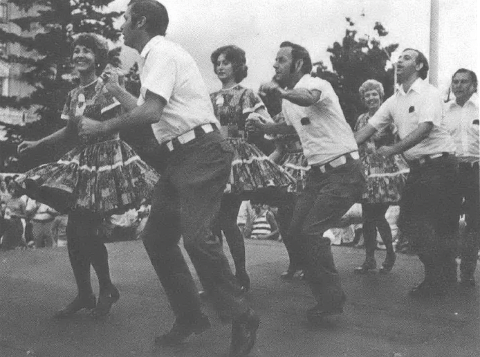 Black and white photo of men and women dancing on a street outside