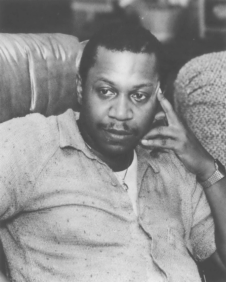Photo portrait of seated Black man with hand to head, looking away from the camera