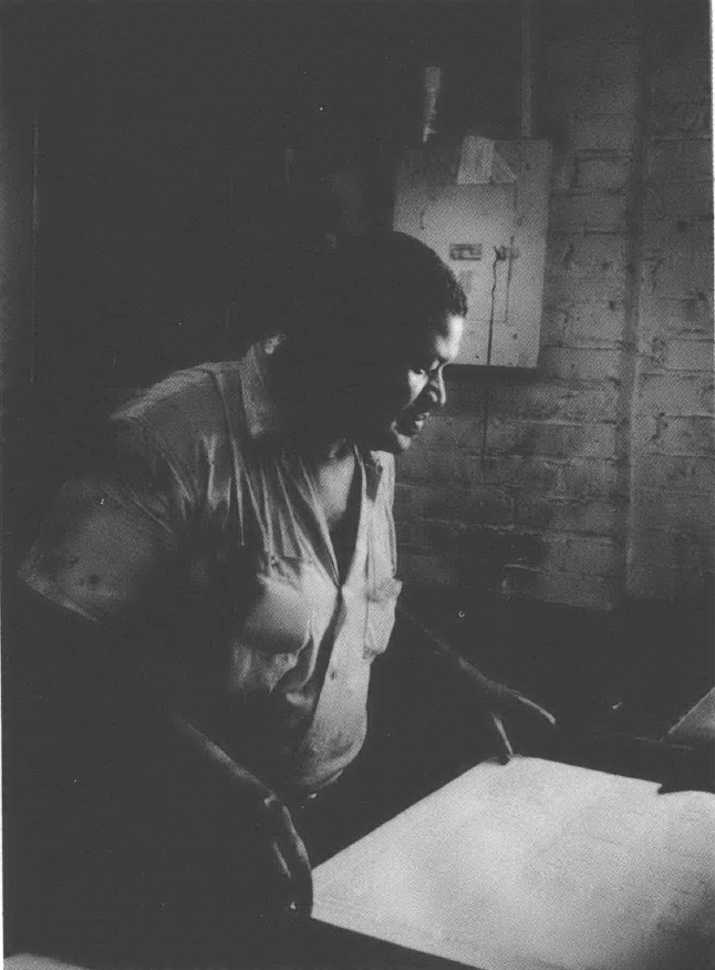 Black and white photo of man standing over paper
