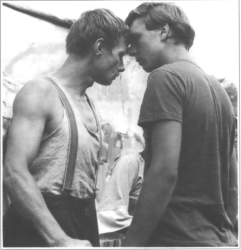 Black and white photo of two men head to head with each other on stage looking into each others' eyes