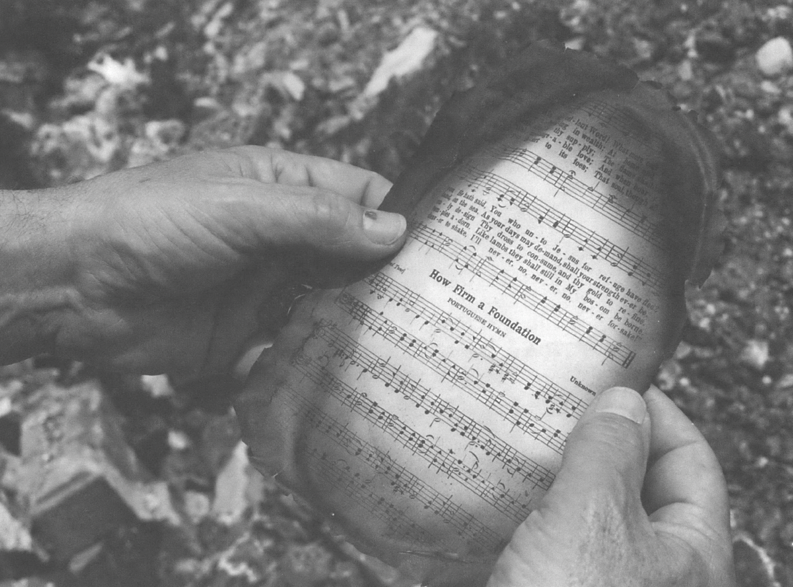 Hands holding a scorched hymnbook page