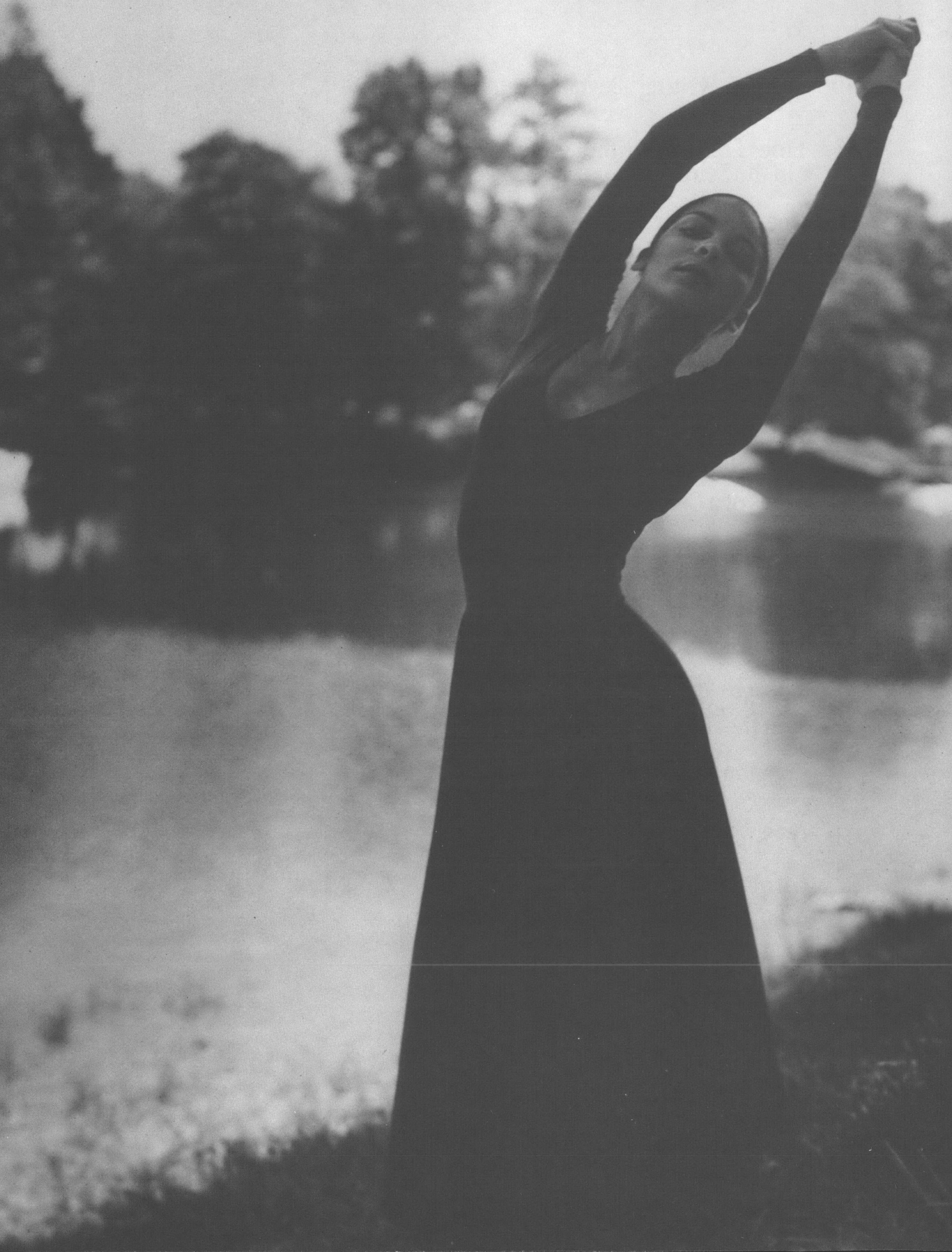 Black and white photo of woman posing as if dancing in front of water