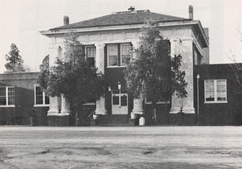 Black and white photo of building with imposing columns and trees in front