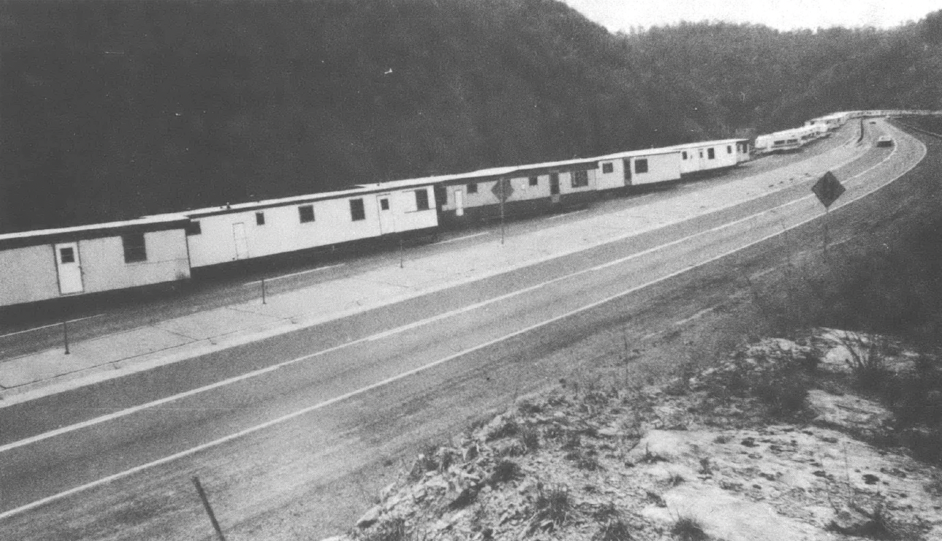 Black and white photo of single-wide trailers lined up along a mountain highway