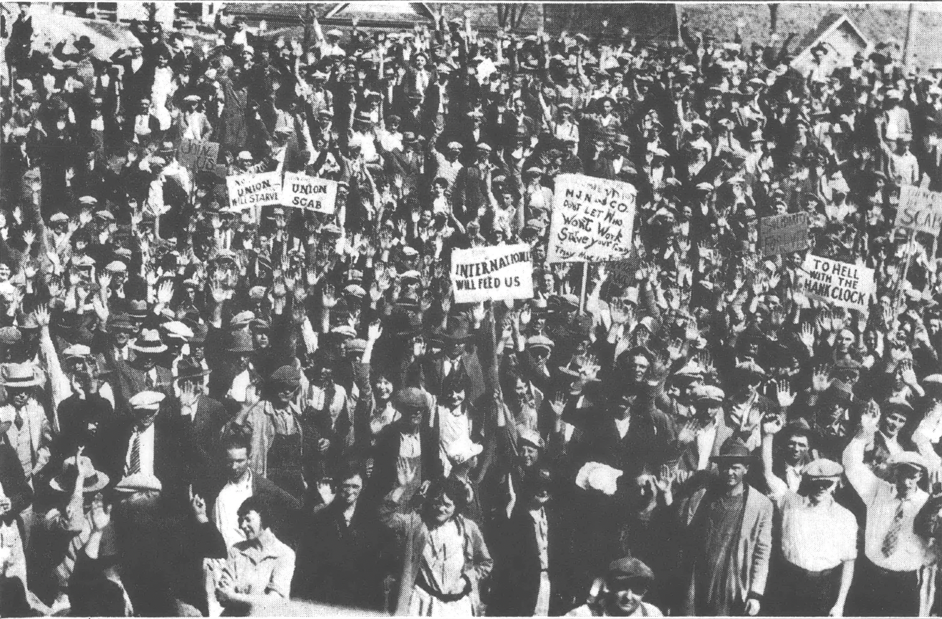 Black and white photo of crowd of people, some of them holding signs