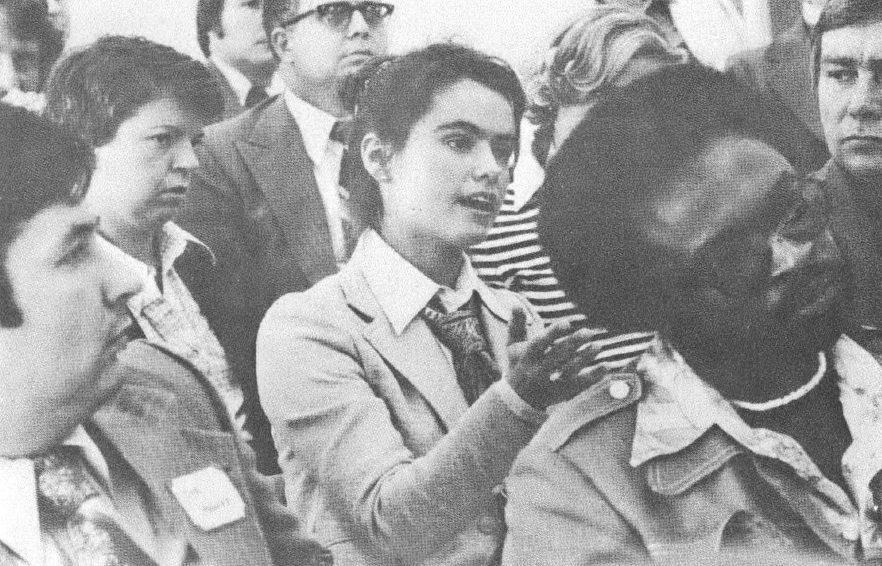 Black and white photo of people listening to speaker