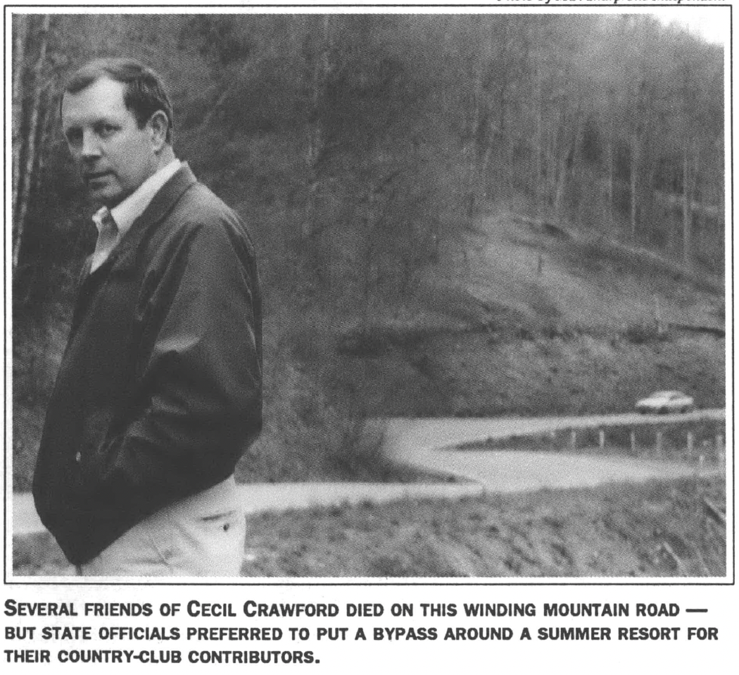 Man in jacket standing at the bottom of a hill by a road