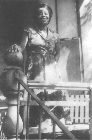 Black and white photo of Black woman standing on porch
