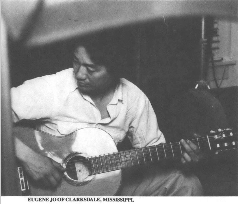 Black and white photo of Eugene Jo holding a guitar