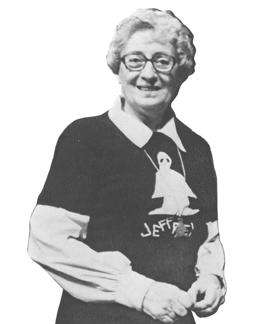 Black and white photo of older woman wearing glasses and t-shirt layered over collared shirt 
