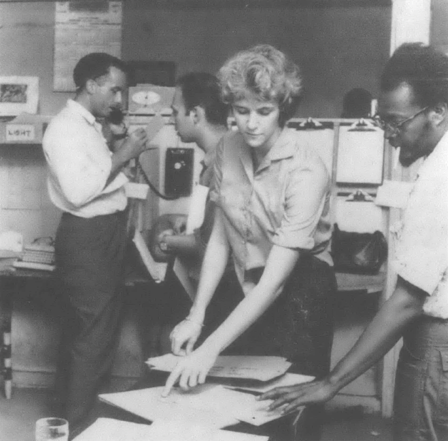 Black and white photo of people in office with papers and phones