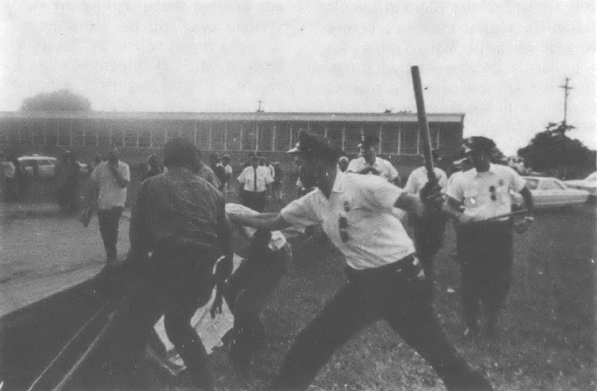 Black and white photo of police beating demonstrators