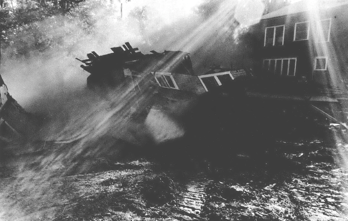 Black and white photo of fallen down house with a ray of sunshine hitting the wreckage