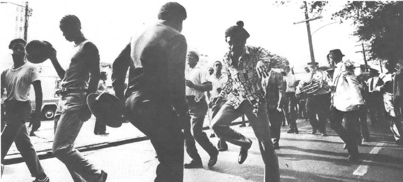 Black and white photo of people, mostly Black, dancing in the street