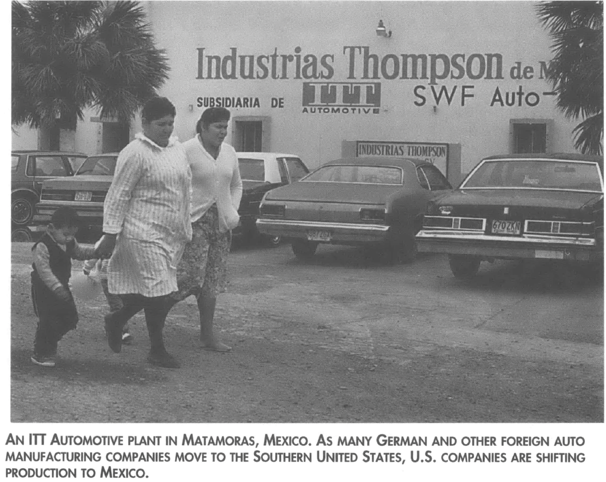 People walk by a factory in Mexico