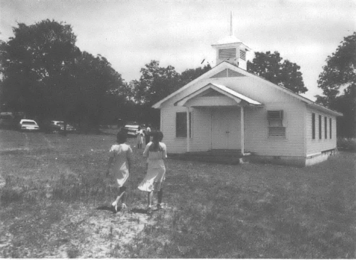 Photo of two women walking into a small churchhouse