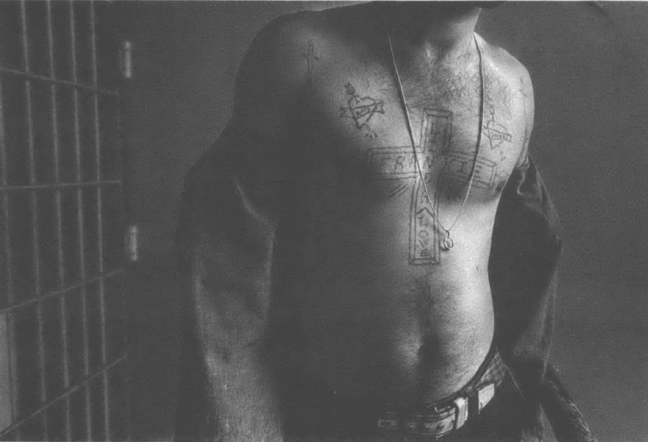 Black and white photo of shirtless man's torso, with tattoos