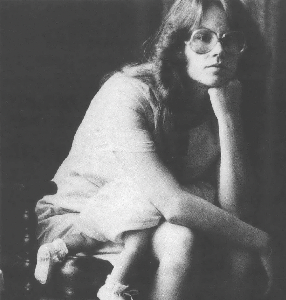 Black and white photo of young white woman in glasses with hand on chin